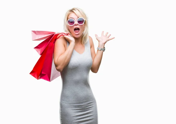 若い美しいブロンドの女性で持株ショッピング バッグ販売のショッピング分離叫んで笑顔で勝利を祝って 手を上げた背景非常に幸せと興奮 勝者式 — ストック写真