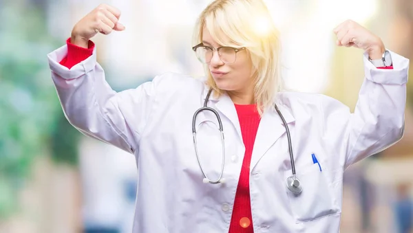 年轻美丽的金发医生妇女穿医疗制服在孤立的背景显示手臂肌肉微笑自豪 健身理念 — 图库照片