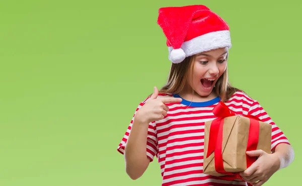 非常に幸せな手と指で指している孤立した背景の上クリスマス帽子 持株ギフトを着た美しい少女 — ストック写真