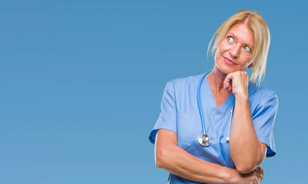 中年金髪看護師外科医医師女性あごを考えて質問 物思いにふける式の手で隔離された背景の上 思いやりのある顔をして笑っています 疑いのコンセプト — ストック写真