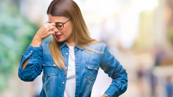 Young beautiful woman over wearing glasses over isolated background tired rubbing nose and eyes feeling fatigue and headache. Stress and frustration concept.