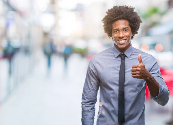 Afro american business man over isolated background doing happy thumbs up gesture with hand. Approving expression looking at the camera with showing success.