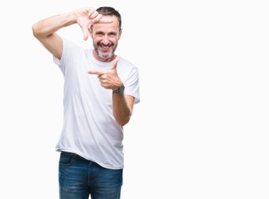 Elle yapma çerçeve ve parmakları ile mutlu yüz gülümseyen izole arka plan üzerinde beyaz t-shirt giyen orta yaş ağarmış komuta sizde. Yaratıcılık ve Fotoğrafçılık kavramı.