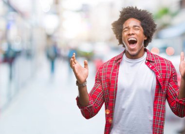 Afro Amerikalı adam kızgın ve silah ile başarı için deli kutluyor izole arka plan üzerinde kaldırdı ve heyecanlı çığlık gözler kapalı. Kazanan kavramı