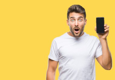 Yakışıklı delikanlı Smartphone ekran izole arka plan üzerinde korkmuş şok bir sürpriz yüz, korkuyor ve heyecanlı korku ifadesi ile gösterilen