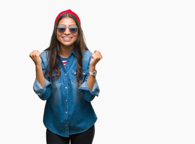 Genç güzel Arap kadın izole arka plan kutlama üzerinde güneş gözlüğü takıyor şaşırttı ve başarı için kaldırdı kollarını açarak hayret ve gözleri açık. Kazanan kavramı.