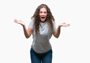 Güzel genç esmer kıvırcık saçlı kız giyiyor rahat bakmak korkuyor ve şok sürpriz ifade ile izole arka plan üzerinde korku ve yüz heyecanlı.