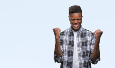 İzole arka plan kutlama üzerinde genç Afro-Amerikan adam şaşırttı ve başarı için kaldırdı kollarını açarak hayret ve gözleri açık. Kazanan kavramı.