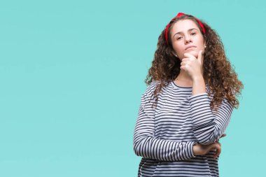 Güzel esmer kıvırcık saçlı Genç kız emin çapraz kollar ve çeneme kaldırdı el ile gülümseme ile kameraya bakarak izole arka plan üzerinde çizgili kazak giyiyor. Pozitif düşünce.