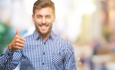 Yakışıklı delikanlı hareketi el ile mutlu yaşasın yapıyor izole arka plan üzerinde. Kameraya bakarak başarı gösteren ile ifade onaylama.