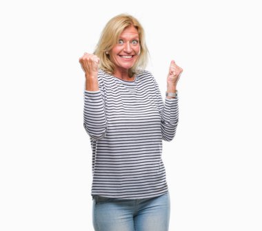 Gülümseyen ve başarı için çığlık orta yaş sarışın kadın izole arka plan çok mutlu ve heyecanlı kaldırdı, silah ile kazanan jest yapıyor. Kutlama kavramı.