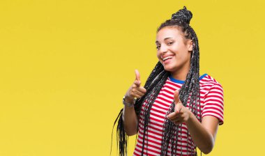 Genç saç Afro-Amerikan kız kameraya mutlu ve komik suratla parmakları işaret izole arka plan üzerinde örgülü. İyi enerji ve vibes.