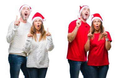 Orta yaş olgun güzel çift beyaz izole arka plan üzerinde Noel şapka kolaj hayrete ve yukarıya bakıyor ve parmakları ile işaret ve silah kaldırdı şaşırttı.
