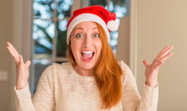 Santa claus şapka çok mutlu ve heyecanlı, kazanan ifade büyük gülümseme ile çığlık zaferini kutluyor giyen ve ellerini kaldırdı Kızıl saçlı kadın