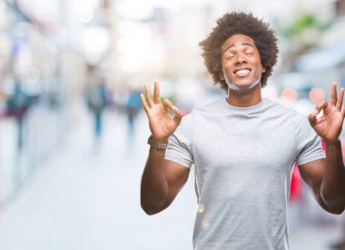 İzole arka plan üzerinde Afro Amerikalı adam rahatla ve gülümseyen gözlerle kapalı parmak jestle meditasyon yapıyor. Yoga kavramı.