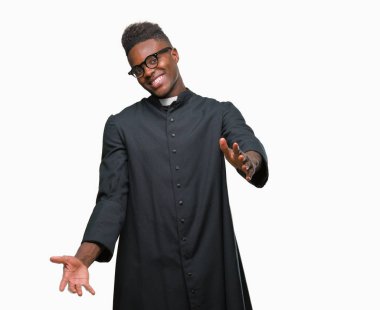 Sarılmak için kollarını açarak gülümseyerek kameraya bakarak izole arka plan genç Afro-Amerikan rahip adam. Neşeli ifade kucaklayan mutluluk.