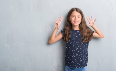 Genç İspanyol çocuğun gösterilen ve parmakları ile işaret grunge gri duvarın üzerinden numara 9 kendinden emin ve mutlu gülümseyerek süre.