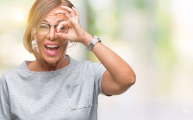 Orta yaş üst düzey İspanyol kadın gülümsüyor, parmakları ile mutlu yüz üzerinden seyir göz el ile ok jest yapıyor izole arka plan üzerinde gözlük.