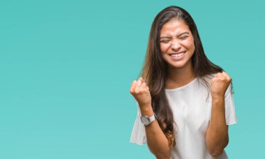 Gülümseyen ve başarı için çığlık genç güzel Arap kadın izole arka plan çok mutlu ve heyecanlı kaldırdı, silah ile kazanan jest yapıyor. Kutlama kavramı.