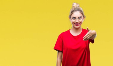 Kırmızı t-shirt ve gözlük üzerinde giyen genç güzel sarışın kadın arka plan olarak tebrik ve konuksever dost sunan karşılıklı gülümseyen izole. Başarılı iş.