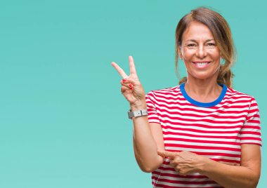Orta yaş İspanyol kadın kıdemli mutlu yüz zafer işareti yaparken kameraya göz kırpıyor ile gülümseyen izole arka plan üzerinde. İki numaralı.