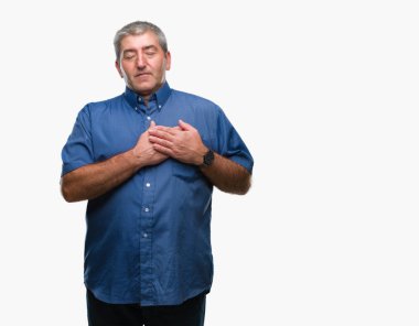 Göğüs kapalı gözler ve yüzünde minnettar jest ile üst düzey yakışıklı ile gülümseyen izole arka plan üzerinde eller. Sağlık kavramı.