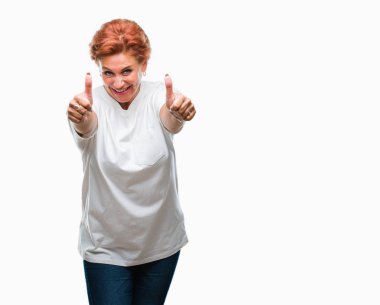 Atrractive üst düzey beyaz Kızıl saçlı kadın izole arka plan onaylama üzerinde el ile pozitif jest yapıyor gülümseyen ve başarı için mutlu başparmak. Kamera, kazanan jest arıyorsunuz.