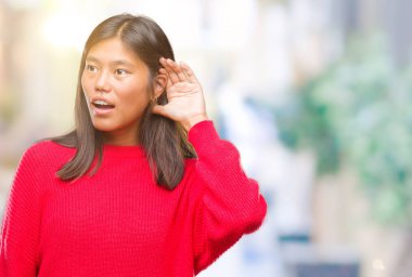 Bir işitme söylenti ya da dedikodu için dinleme kulak üzerinde el ile gülümseyen izole arka plan üzerinde kış kazak giyen genç Asyalı kadın. Sağırlık kavramı.