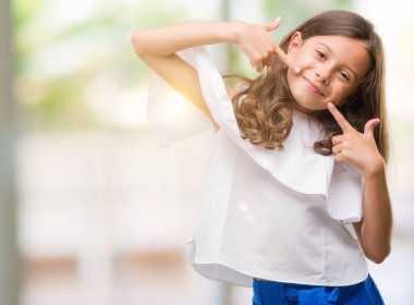 Esmer Latin kız kendinden emin gösterilen ve işaret parmakları diş ve ağız ile gülümseyen. Sağlık kavramı.