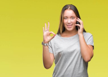 Genç güzel beyaz kadın parmakları, mükemmel sembolü olan ok işareti yapıyor izole arka plan üzerinde Smartphone'da söz