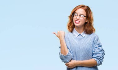 İzole arka planı arıyorum ve başparmak yanında yukarıyı mutlu yüz ile gülümseyen kış kazak giyen genç güzel kadın.