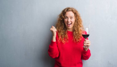 Duygu tezahürat genç Kızıl saçlı kadın gurur çığlık ve zafer ve başarı çok heyecanlı, kutluyor şarap içme gri grunge duvarın üzerinden