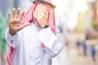 Üst düzey Arap adamın üzerinden keffiyeh giydiğini izole elleriyle gözlerini kapsayan arka plan ve stop jest ile acı ve korku ifadesi. Utandım ve negatif kavramı.