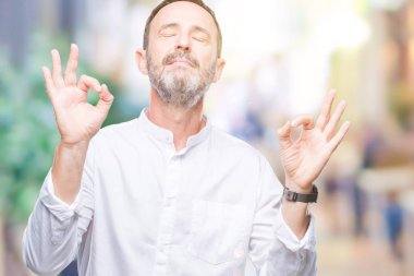 Orta yaş ağarmış komuta sizde izole arka plan üzerinde dinlenmek ve gülümseyen gözlerle kapalı parmak jestle meditasyon yapıyor. Yoga kavramı.