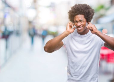 Yüksek sesle müzik gürültü rahatsız ifade parmaklarıyla kulaklarıyla kapsayan izole arka plan üzerinde Afro Amerikalı adam. Sağır kavramı.