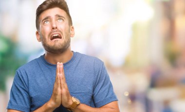 Yakışıklı delikanlı yalvarıyor ve umut ifade yüzünde çok duygusal ve endişe ile birlikte elleriyle dua izole arka plan üzerinde. Bağışlanmak. Din kavramı.