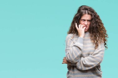 Stresli ve gergin elle çivi ısırma ağzına bakarak izole arka plan üzerinde kış kazak giyen güzel esmer kıvırcık saçlı Genç kız. Anksiyete sorunu.