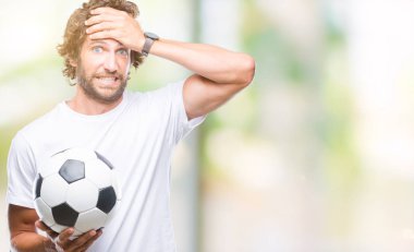 Baş, el ile vurguladı izole arka plan üzerinde futbol futbol topu tutan Latin asıllı yakışıklı modeli şok utanç ve sürpriz suratla, öfkeli ve sinirli. Korku ve hata için üzgün.