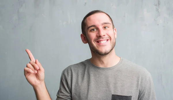 Young Caucasian Man Grey Grunge Wall Very Happy Pointing Hand — Stock Photo, Image