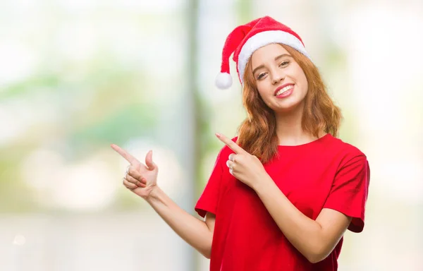 年轻美丽的女人在孤立的背景下戴着圣诞帽微笑着 看着相机指着两只手和手指的侧面 — 图库照片