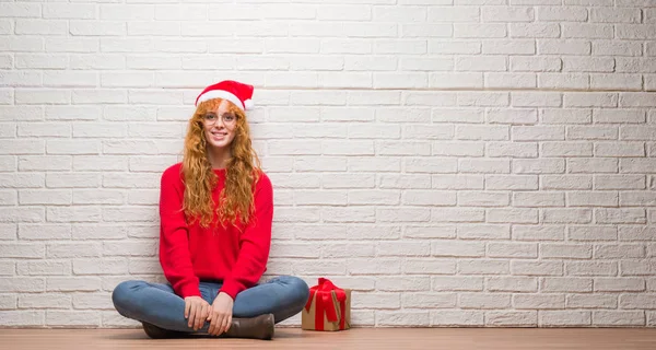 Young Redhead Woman Sitting Brick Wall Wearing Christmas Hat Happy — Stock Photo, Image