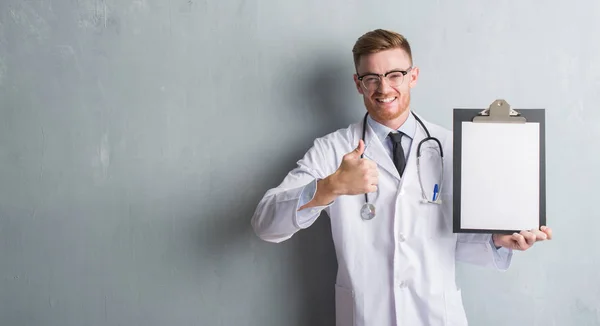 Jeune Rousse Médecin Homme Sur Mur Gris Grunge Tenant Presse — Photo