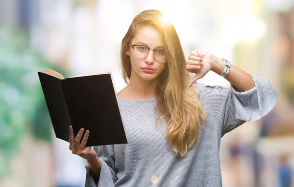 Genç güzel sarışın kadın kızgın yüzü, eksi işareti aşağı antipati başparmak ile gösterilen, ret kavramı ile izole arka plan üzerine bir kitap okuma