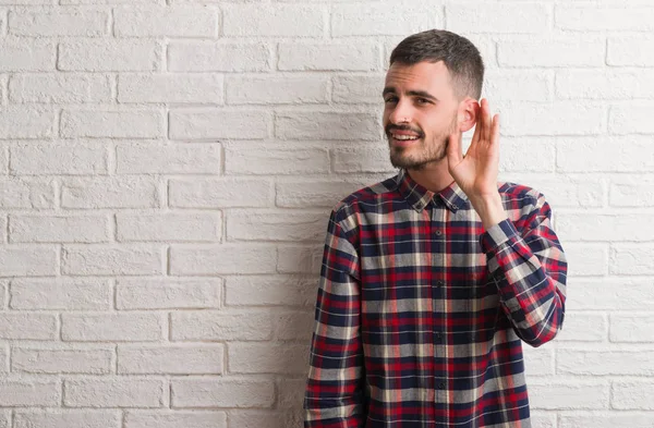 Ung Vuxen Man Står Över Vit Tegelvägg Ler Med Handen — Stockfoto