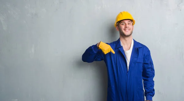 Joven Caucásico Hombre Sobre Gris Grunge Pared Usando Contratista Uniforme — Foto de Stock