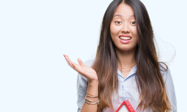 Young asian woman real state agent holding house isolated background very happy and excited, winner expression celebrating victory screaming with big smile and raised hands