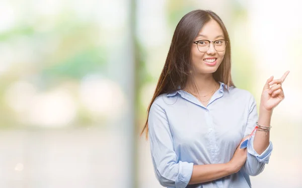 年轻的亚洲商业妇女戴着眼镜在孤立的背景上 脸上露出了笑容 用手和手指指着侧面看着相机 — 图库照片