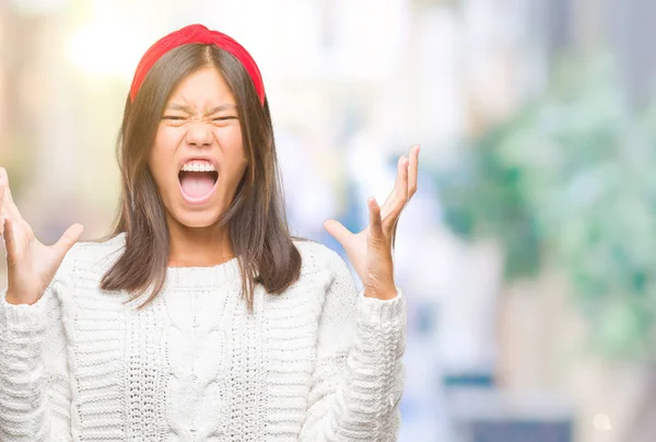 Üzerinde kış kazak giyen genç Asyalı kadın arka plan deli izole ve deli bağırarak ve agresif ifade ve silah kaldırdı bağırıyor. Hayal kırıklığı kavramı.