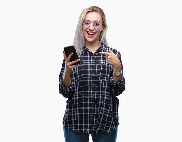 非常に幸せな手と指で指している分離の背景にスマート フォンを使用してメッセージを送信する若いブロンドの女性のテキスト メッセージ — ストック写真