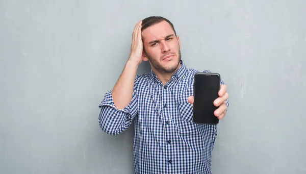 Joven Hombre Caucásico Sobre Pared Grunge Gris Que Muestra Pantalla —  Fotos de Stock